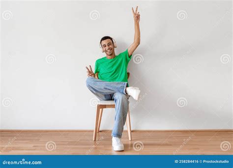 Emotional Arab Man Sitting on Chair Over White Wall, Using Modern ...