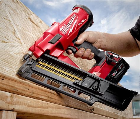 Impact driver and framing nailer fastening wood studs together during house framing construction.