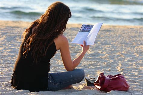 Woman Reading Book In Her Hand And Sitting On The Beach - Boxist ...