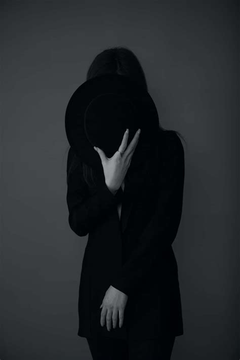 Download a woman in black with a hat covering her face | Wallpapers.com