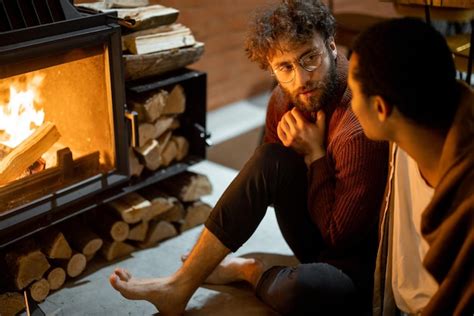 Two men sitting together by the burning fireplace at cozy home ...