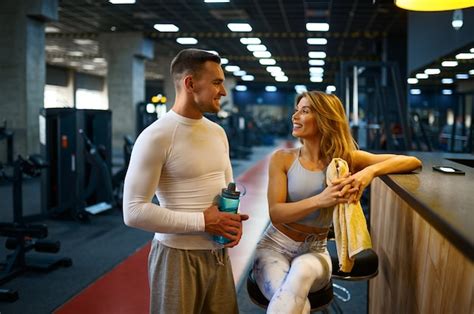 Sportive couple relax at the counter in gym bar after fitness training ...