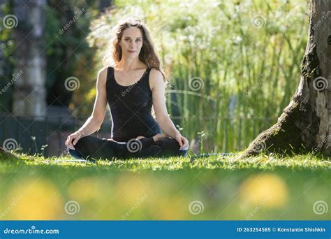 Beautiful Woman Sitting in the Lotus Position on Yoga Mat and Looking ...