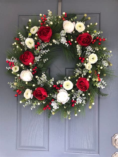 a wreath with red and white flowers on the front door