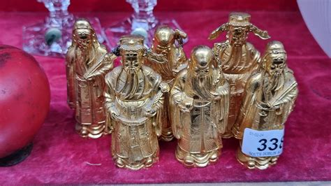 A collection of six heavy brass toned figures depicting wise Chinese men.