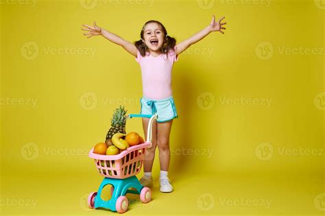 Adorable little girl raising her arms up, expressing happiness standing ...