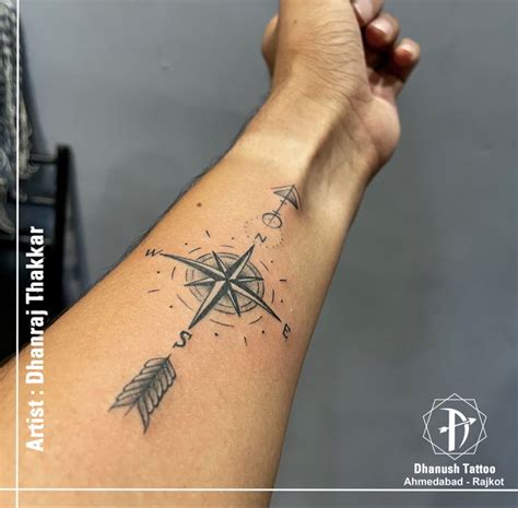 a person's arm with a compass tattoo on it and an arrow in the middle