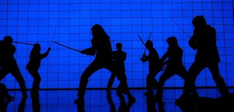 Four figures in action, including a man with a top knot crouching and shooting, a figure in a green