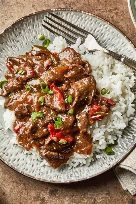A bowl of slow cooker pepper steak, served over white rice