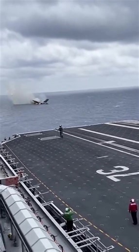 Fighter Jet Explodes Moments After Vertical Takeoff From Aircraft Carrier At Sea — A routine flight operation aboard an aircraft carrier turned catastrophic when one of two fighter jets lifting off the deck suddenly exploded midair just as it began a vertical climb, sending fire and debris downward as stunned crew members watched from below. The video shows two jets launching in close succession from the carrier’s deck. Both aircraft rise cleanly at first, hovering briefly above the ship as exha
