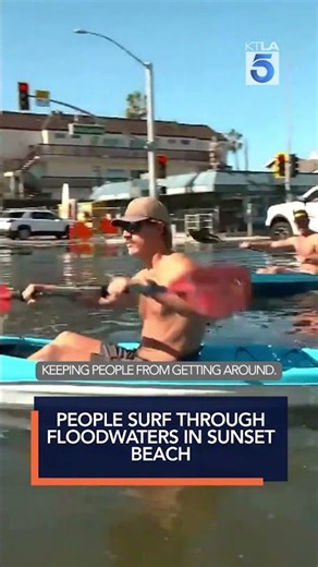 People surf through floodwaters in Sunset Beach