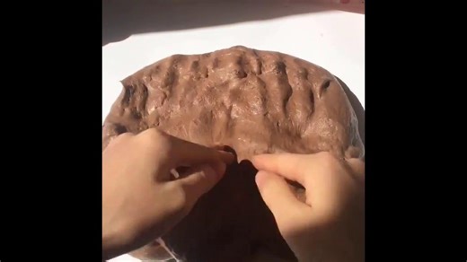 Poking and pressing brown bubbly glossy slime creating smooth air bubble pops