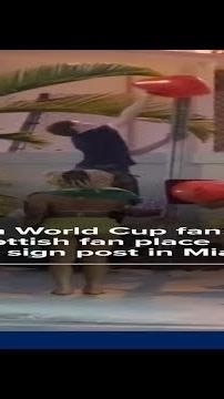 Brazilian World Cup fans help Scottish fan place cone on sign post in Miami