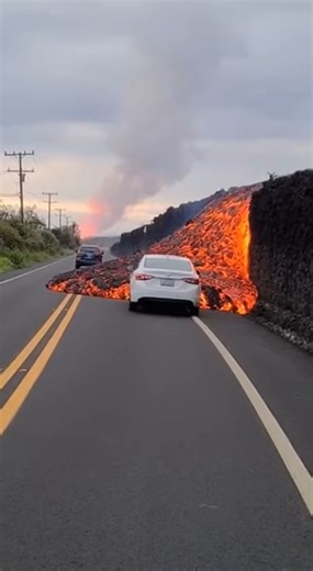 Fiery Chaos on the Highway as Lava Overtakes Roadway November 30, 2025 – Hawaii What began as a scenic roadside stop turned into a frantic dash for survival when a fresh lava breakout surged down the mountainside and toward a crowded highway. Witnesses say the lava flow had been slow earlier in the day—thick, sluggish, and predictable. But just after 5 p.m., the vent at the upper ridge cracked open with a violent hiss, sending a new channel of lava racing downslope. This breakout was much hotter