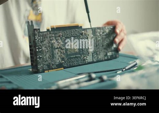 A person is repairing a computer graphics card in a home workshop. Tools and parts are spread on a table. The environment shows focus on fixing and technical work Stock Video Footage - Alamy