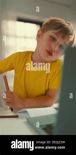 A young boy is focused on his screen while learning online. He holds a pencil in his hand and looks curious as he interacts with the computer. It is morning and the room is well-lit Stock Video Footage - Alamy