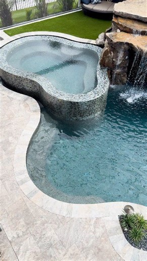 ✈️ Why fly to a resort… when you can live in one? This Insane Pool features a natural rock grotto, a beautiful spa with an infinity edge, a sun shelf, and a pool cage enclosure. #insanepools #lucaslagoons #backyardgoals | Lucas Lagoons