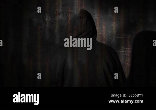 Anonymous hooded hacker sitting with back to camera during tense police interrogation in a dark station room, glowing matrix style code overlay, cybercrime investigation, cyber security and digital fo Stock Video Footage - Alamy