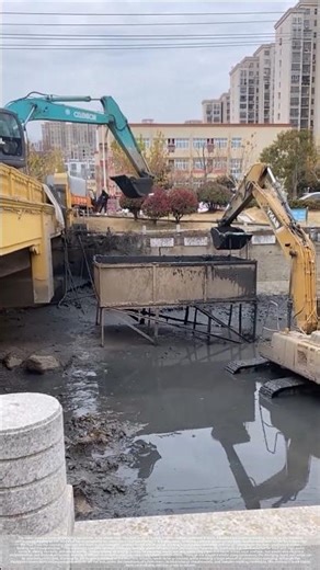 Two excavators work in tandem to bring the silt from the riverbed ashore.