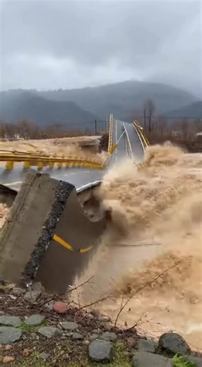 Man Runs for His Life as Floodwaters Tear Bridge Apart Behind Him Sichuan Province, China — A routine inspection turned into a desperate escape when surging floodwaters ripped through a roadway bridge, forcing a worker to sprint for safety as the structure collapsed just feet behind him. The dramatic moment was captured on video as heavy rain swelled the river beyond its limits. The footage opens with brown, fast-moving water slamming into the bridge supports beneath a gray sky. The river roars,
