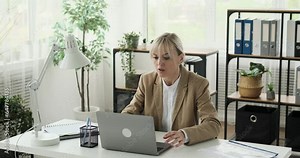 An angry woman office worker is seen getting frustrated and upset, leading her to close her laptop abruptly. Her facial expressions clearly express negative emotions in response to a disappointing. Stock Video