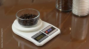 Coffee beans on electronic scales. Coffee in transparent bowl on kitchen electric scale. Measuring the weight of fresh roasted coffee beans