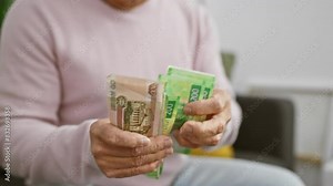 Mature man counting russian rubles in a home interior, illustrating finance and retirement.