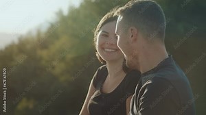 Happy couple in love in the countryside on a sunny day. Enjoying nature and the view. Young man and woman sitting on the bench.