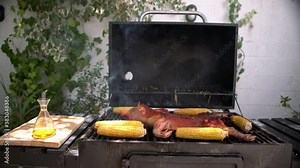 4K, Crispy roasted piglet which are being grilled on barbecue with corn on the cob. Close up of delicious whole pig over on BBQ grill, Home cooking. Chef cooking tasty pork in backyard.-Dan
