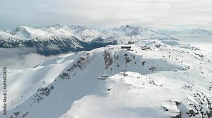 Aerial drone footage of Whistler mountain, BC, ski hill on a sunny day, Whistler peak, ski run, skier, winter sport. 4K 24FPS.