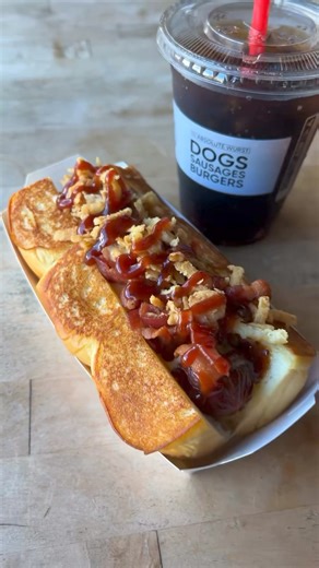 No #Stagecoach? 🎶 You can still eat like a Cowboy! 🤠 Saddle up for one of our favorite dogs topped with smoked bacon, cheddar cheese sauce, crispy onions and BBQ sauce. Wrangle in some yum at #DogHaus! 🔥 | Dog Haus Biergarten