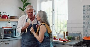 Couple, singing and spoon in kitchen while cooking dinner together for healthy vegetables, prepare or bonding. Mature, people and karaoke in home with utensil for food meal prep, relationship or joy