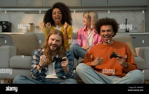 Four multiracial people friends students fun weekend at home Caucasian men guys males playing console video game addicted win lost African American Stock Photo - Alamy
