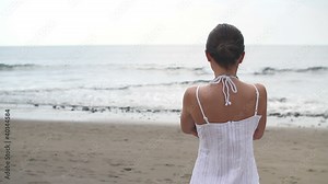 Lonely woman standing at the beach and looking at sea
