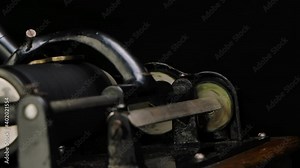Macro detailed shot of the mechanisms of a classic phonograph on a black studio background. Rotating parts of a retro musical instrument. Close up. Slow motion.