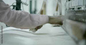 Traditional cotton textile production in India. Male factory worker uses wooden hand loom, weaving thread into cotton fabric used in the garment industry.