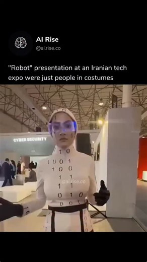 AI Rise on Instagram: "At the 2025 Kish Inox Tech Expo in Iran, a display billed as “advanced humanoid robots” quickly went viral when attendees and online viewers realized the figures were people in costumes, not actual autonomous machines. Videos from the event show a man and a woman in binary-pattern outfits and makeup moving in a mechanical style, but close looks revealed natural breathing, blinking, and human features that clearly gave them away. Organizers and tech commentators later clari
