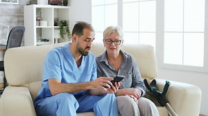 Nurse helps woman use app on mobile phone - Free Stock Video
