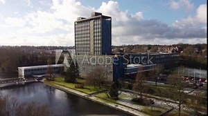 Aerial view Pilkington's glass head office, a modern blue high-rise with shared office space, dolly right