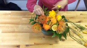 1.5K views · 30 reactions | Watch as Lori creates a bright and colorful arrangement of Pincushion Protea and Ranunculus, adding the tropical zest with foliage and lemons. The colors of yellow and orange will sure to brighten anyone’s day! | Florists' Review | Facebook