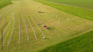 Hay harvesting by two tractors in agronomic meadow field. Work in agronomic farm for making business and production organic eco bio animal feed
