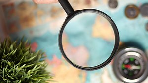 hand holding magnifying glass on an open map