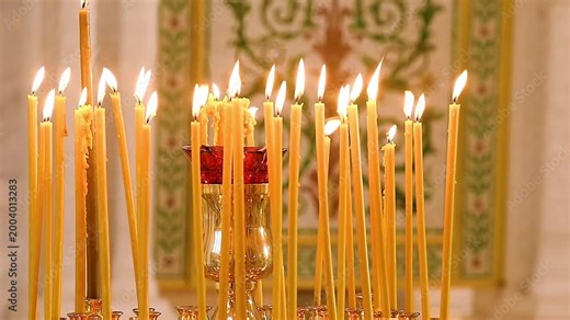 A golden candlestick with numerous lighted candles on the background of an altar from an Orthodox church.