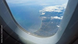 Airplane window view above clouds. Looking outside the window during an airplane travel. Flight above clouds with scenic view. Passenger looking oustide window.