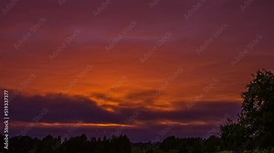 Low angle shot over red sunset sky with dark cloud movement in timelapse. Dark red sunlight sky over rural landscape.