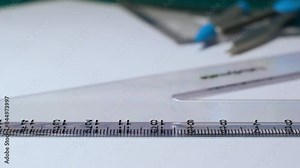 Close-up pencil drawing straight line across a plastic 60 degree set square white paper copy space