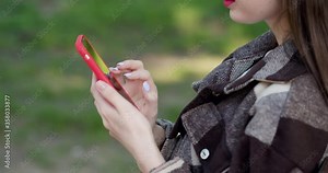 Young girl using mobile smart phone in the park during spring or summer time. Internet, using smartphone, close-up fashion model, post in instagram, facebook concept. Girl using mobile phone in a park