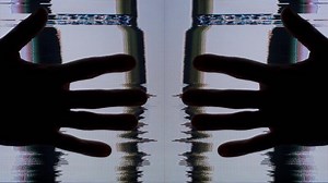 Two hands are shown in front of a television screen