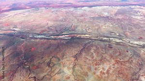High altitude aerial view from airplane of Australian desert located in central Australia showing the dry sandy and rocky natural environment with typical yellow red colours 4k quality animation