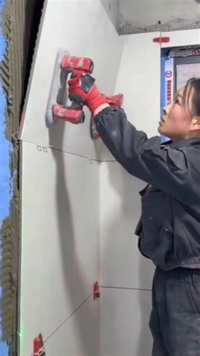worker installing large wall tiles using electric suction tool